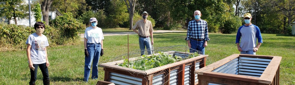 Interfaith Garden board members and Matt Knowlton pose at the garden with raised planters