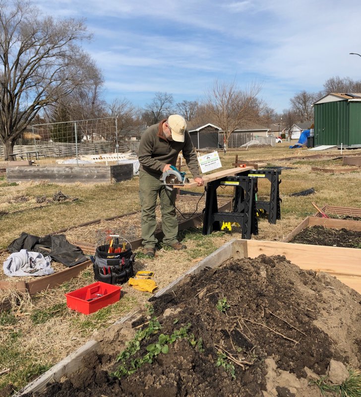 Robb Jacobson cuts a board to length at the Unite4Health garden