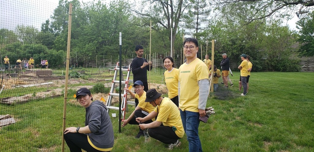 Many volunteers from ForColumbia are putting up a tall fence of plastic netting at Unite4Health Community Garden.