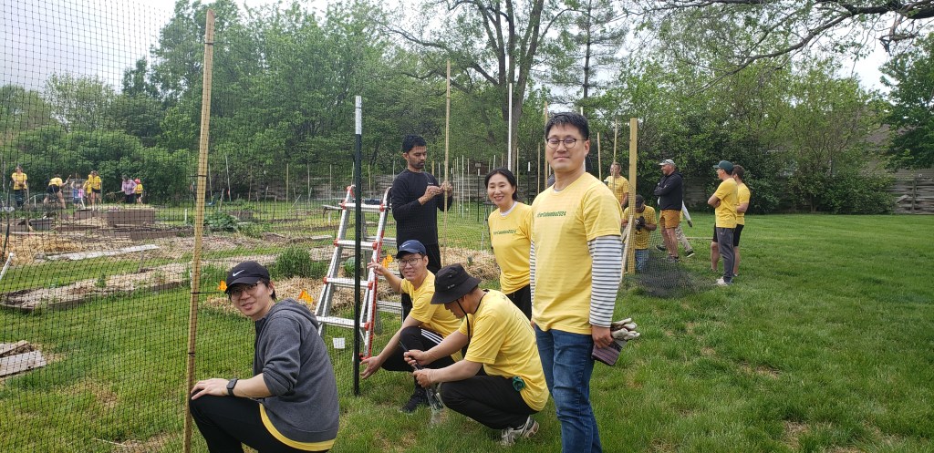 volunteers work on installing a tall netted fence to prevent deer from entering the Unite4Health garden