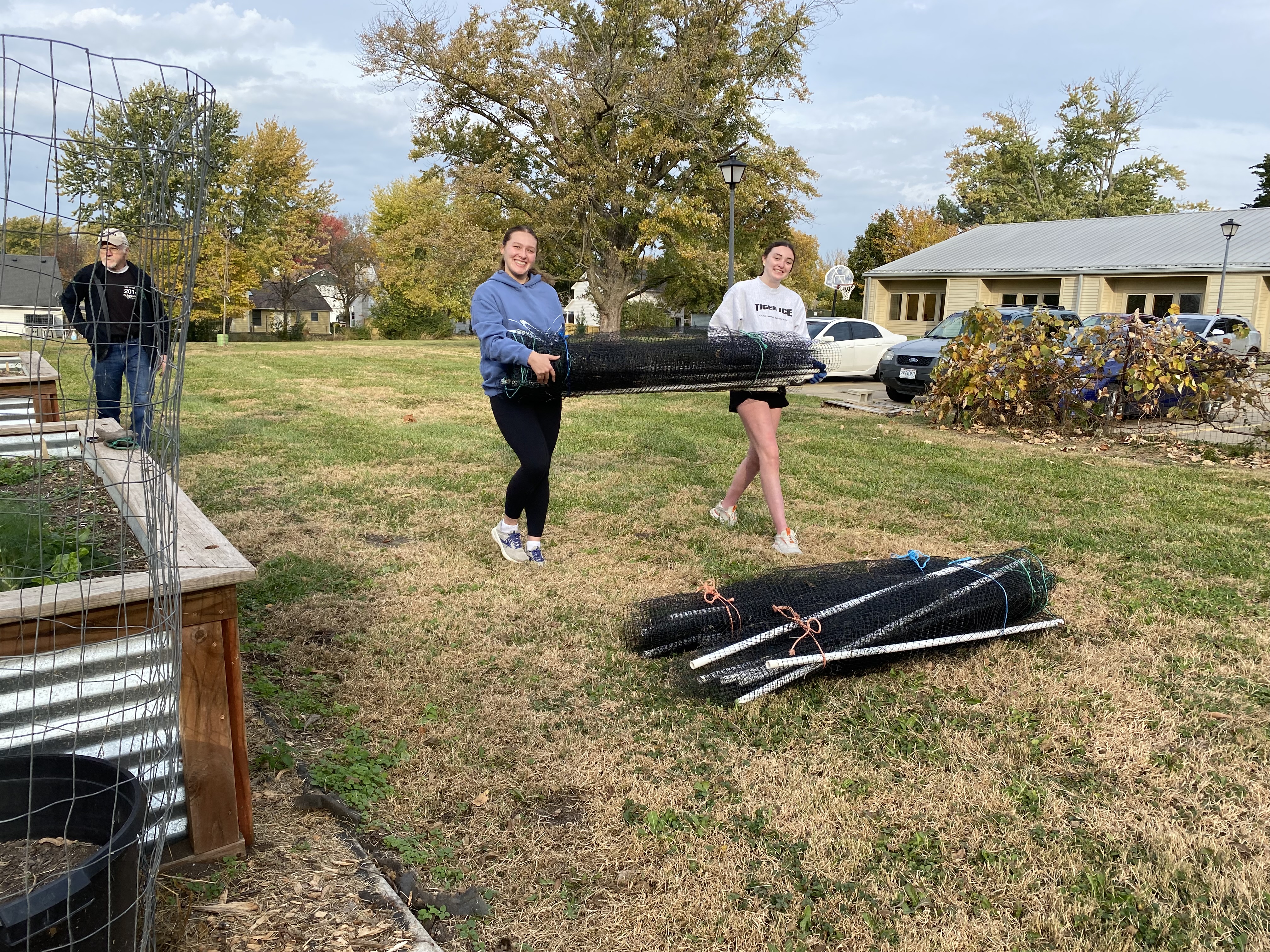 two volunteers from Tolton High School carry fencing material at Interfaith Garden