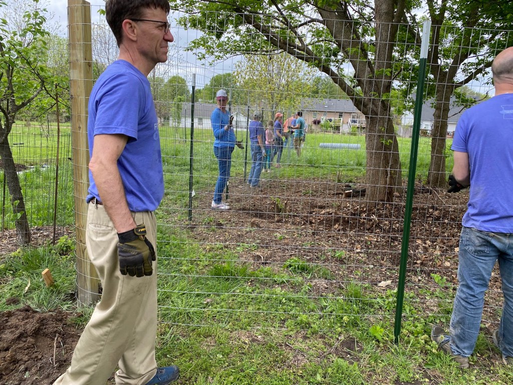 Several For Columbia volunteers work to put up a 6-foot deer fench around a fruit tree planting at Interfaith garden.